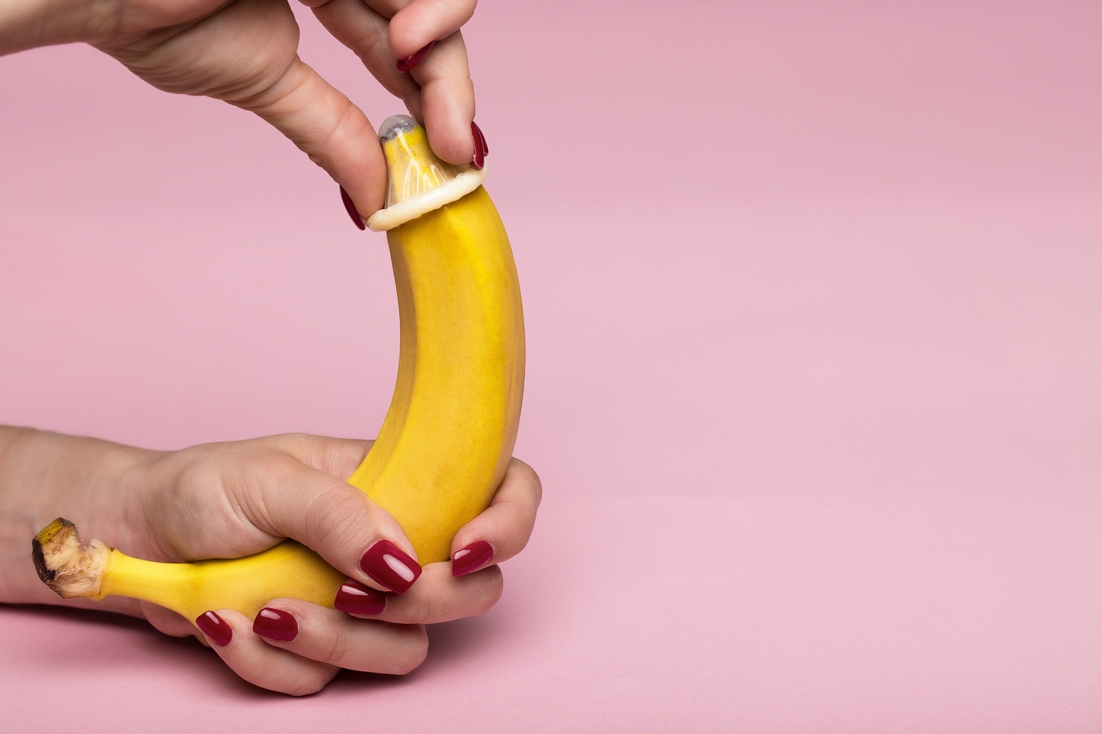 woman pulling condom on banana, bought in adult webshop