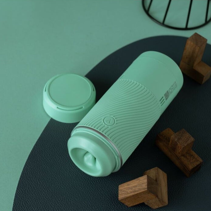 Mint green male masturbator on a green and black surface with wooden blocks.