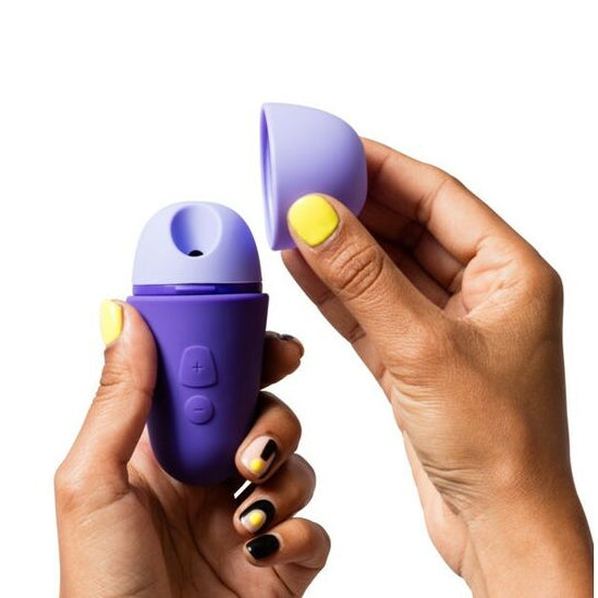 Hand holding two purple and white sexual wellness devices against a white background