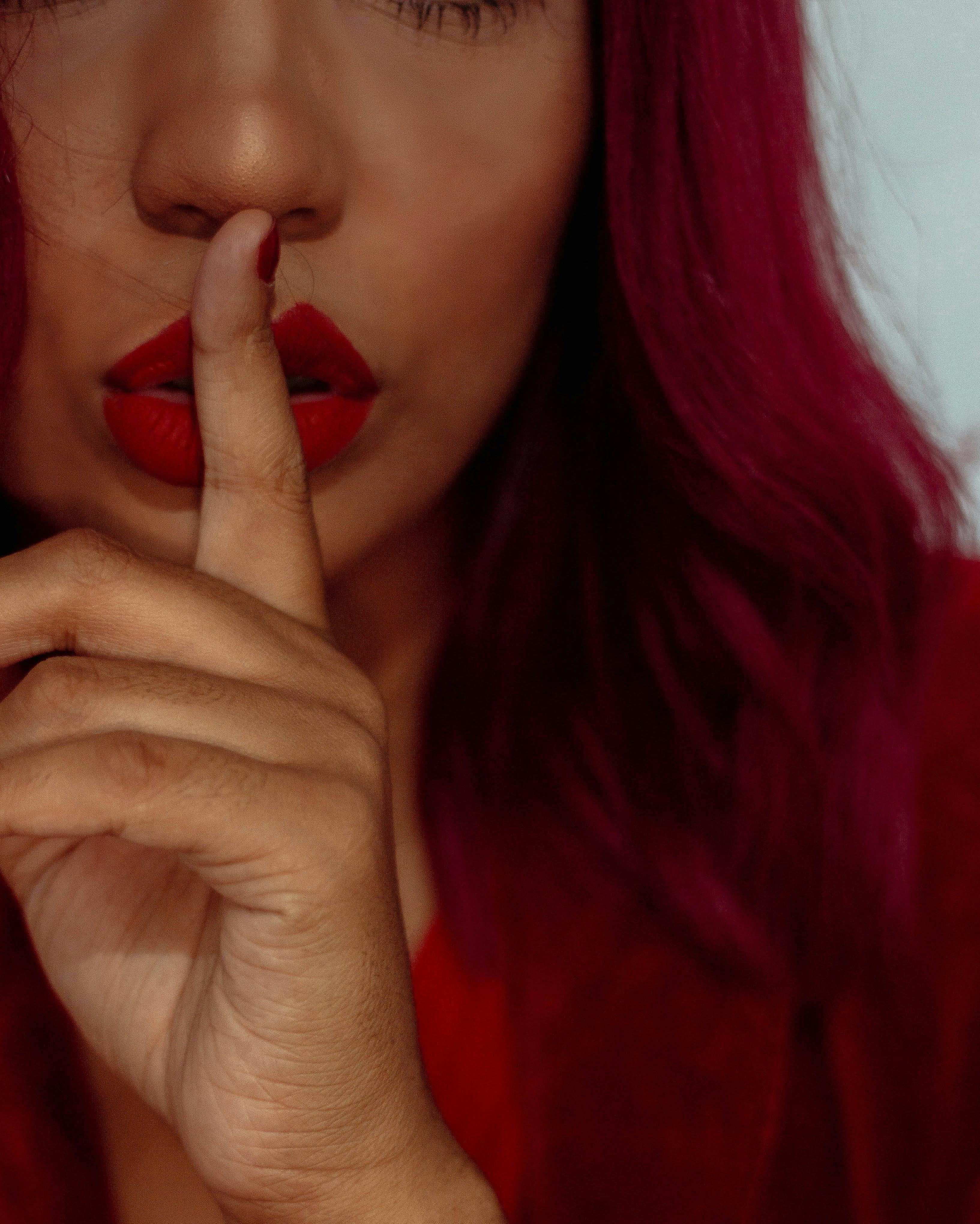 red hair woman holding her finger in front of her face