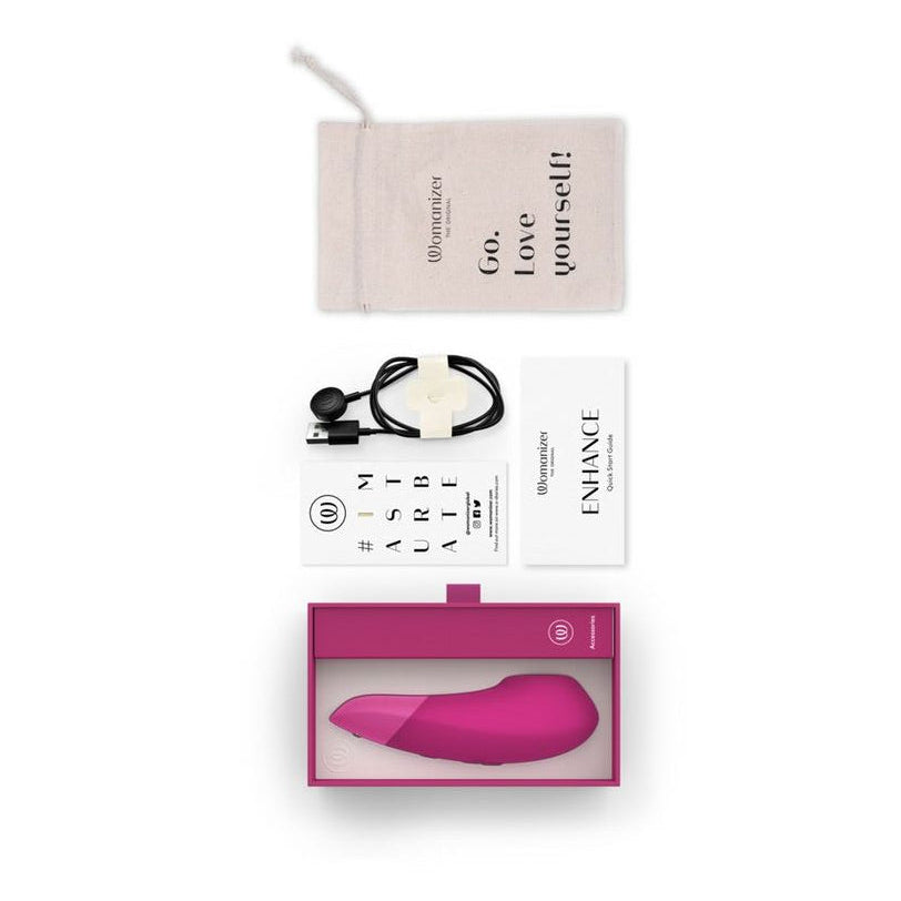 Womanizer branded Erotic Product packaging with a pink object, black charging cables, and a motivational card on a white background