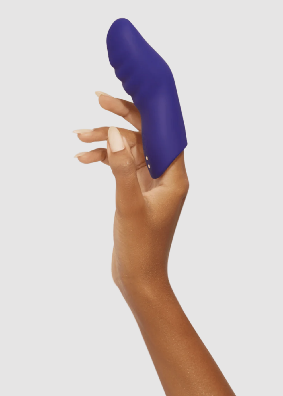 Hand holding a purple finger vibrator sleeve against a light gray background