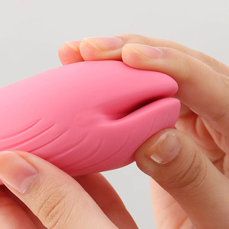 Pink silicone sexual wellness device held between hands against a light gray background