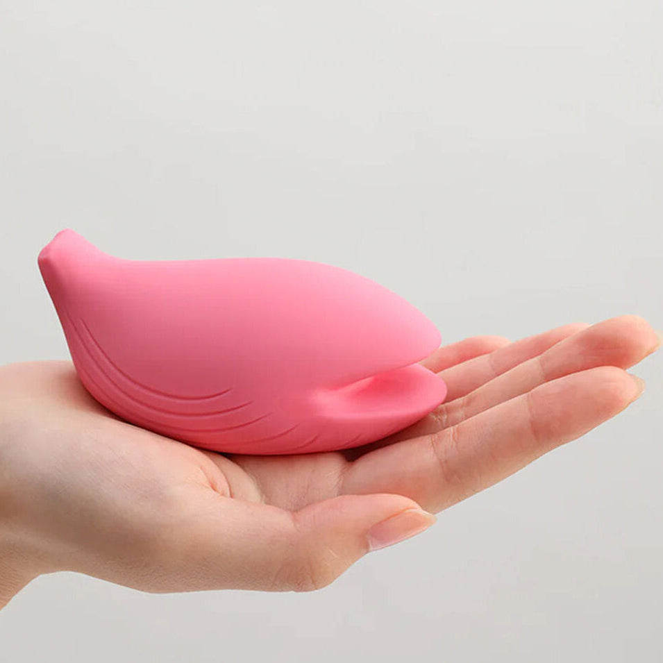 Pink whale-shaped iroha vibrator held in a hand against a light gray background