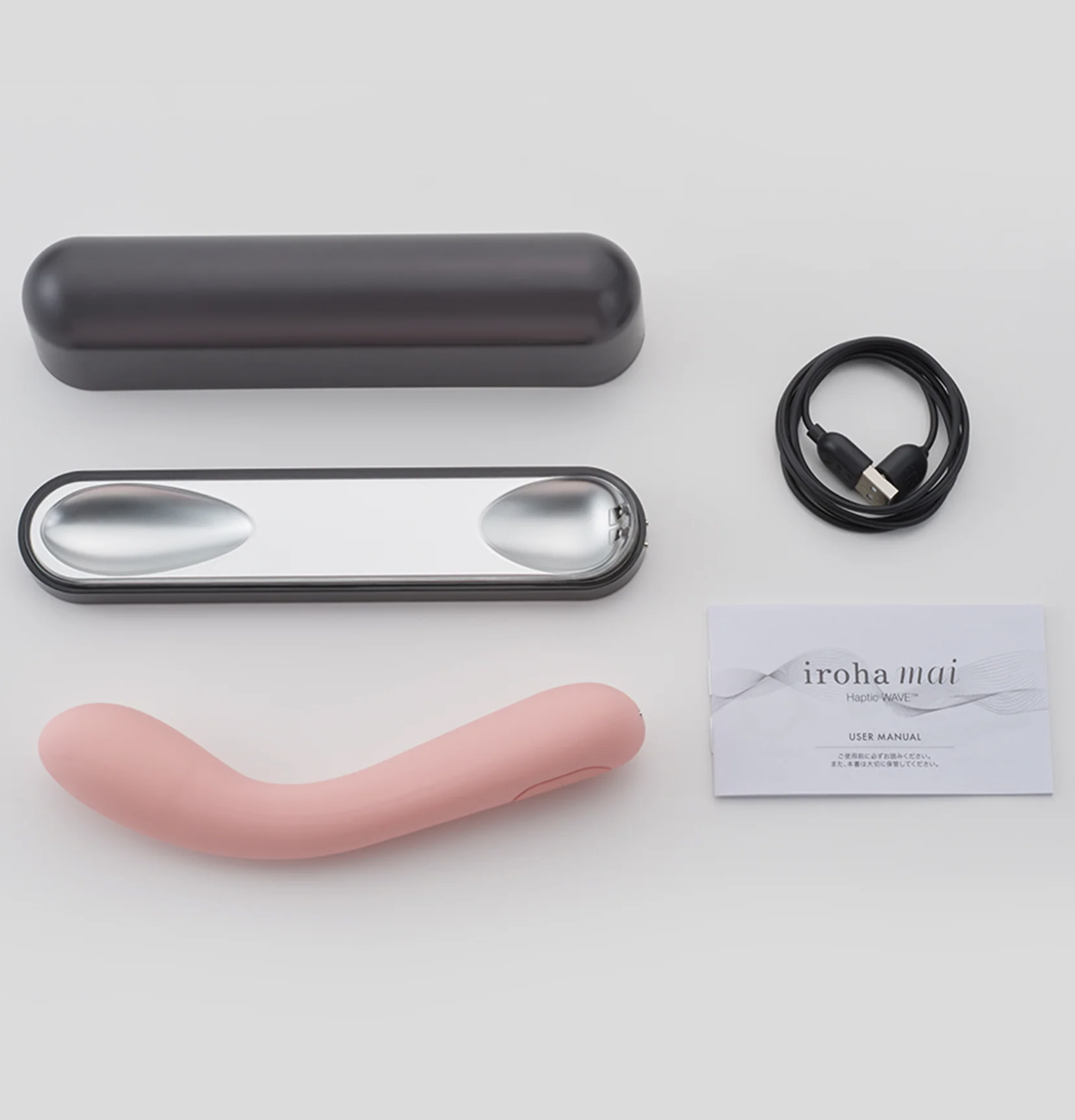 Pink curved adult toy, black case, silver spoon, USB cable, and business card on a white background