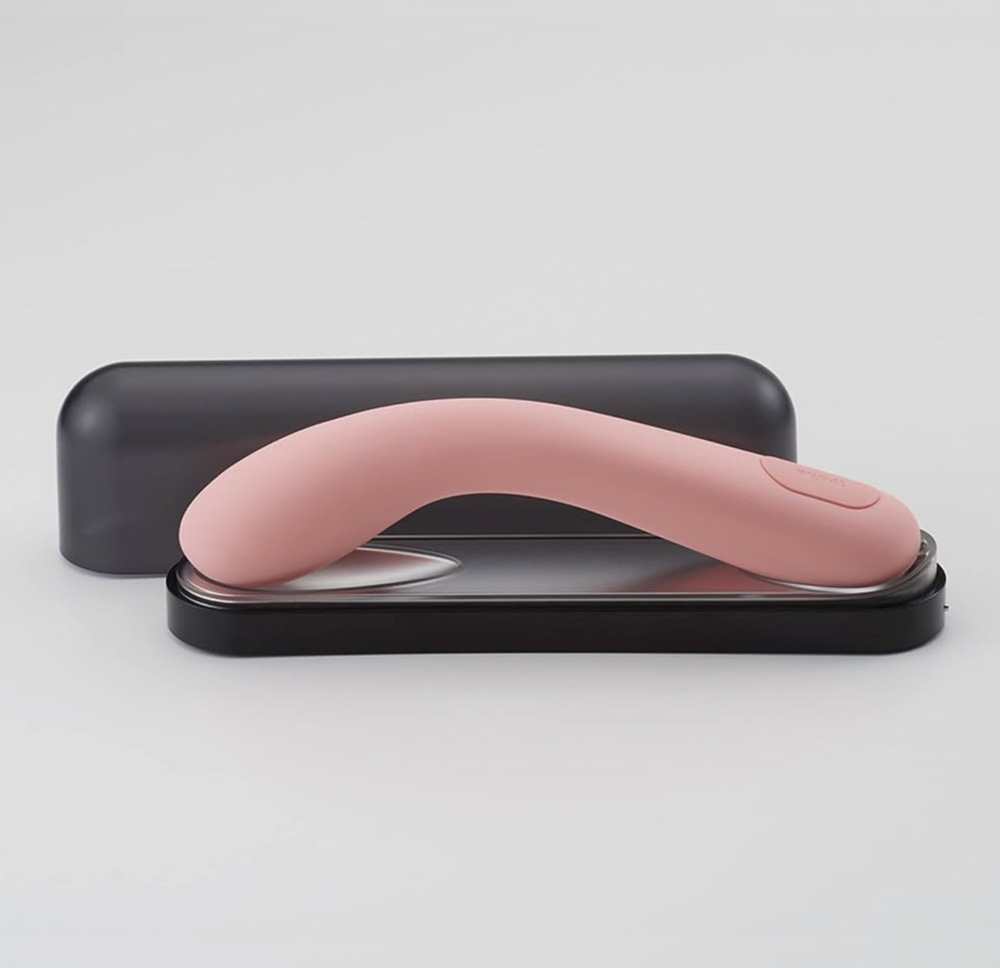 Pink handheld sex toy device with a black case on a light gray background