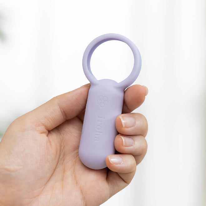 Hand holding an iroha purple vibrating cock ring with a white background