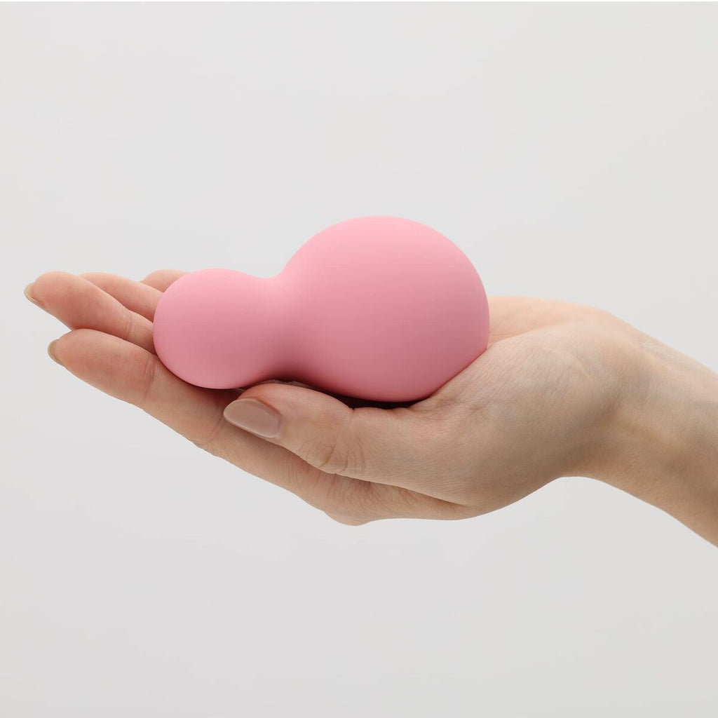 Pink heart-shaped vibrator held in a hand against a light gray background