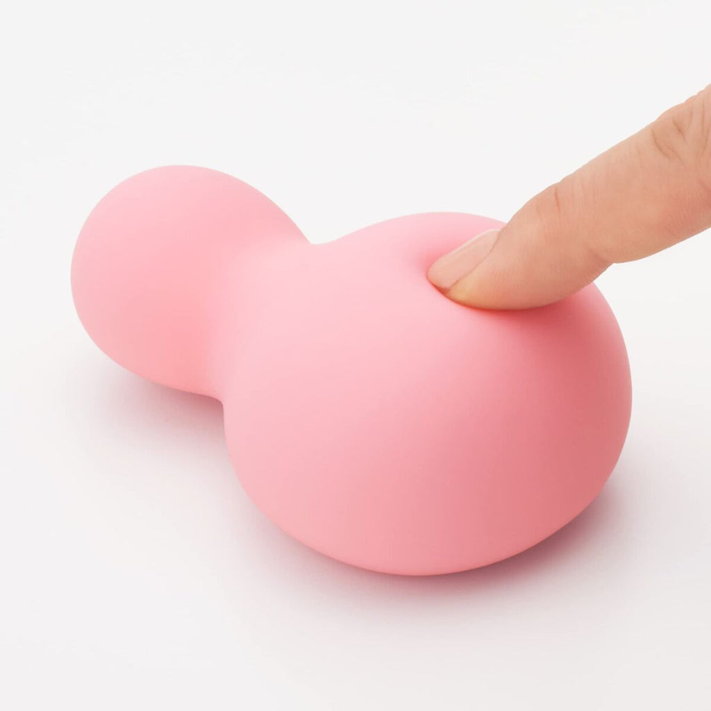 Pink stress ball with a finger pressing on it against a white background