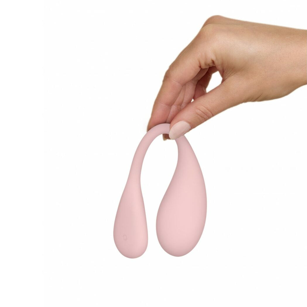 Hand holding a pink silicone egg vibrator on a white background