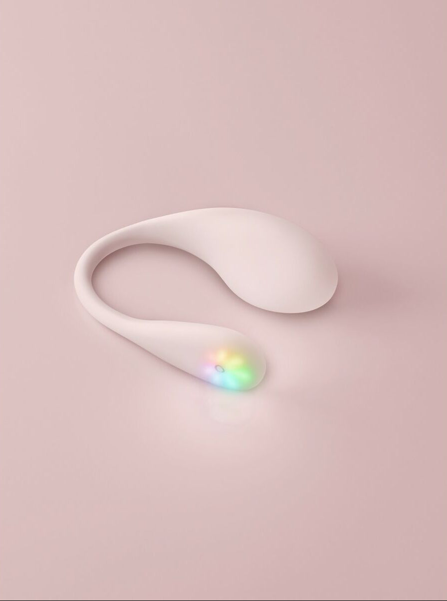 White electronic sexual wellness device with colorful light on a pink background