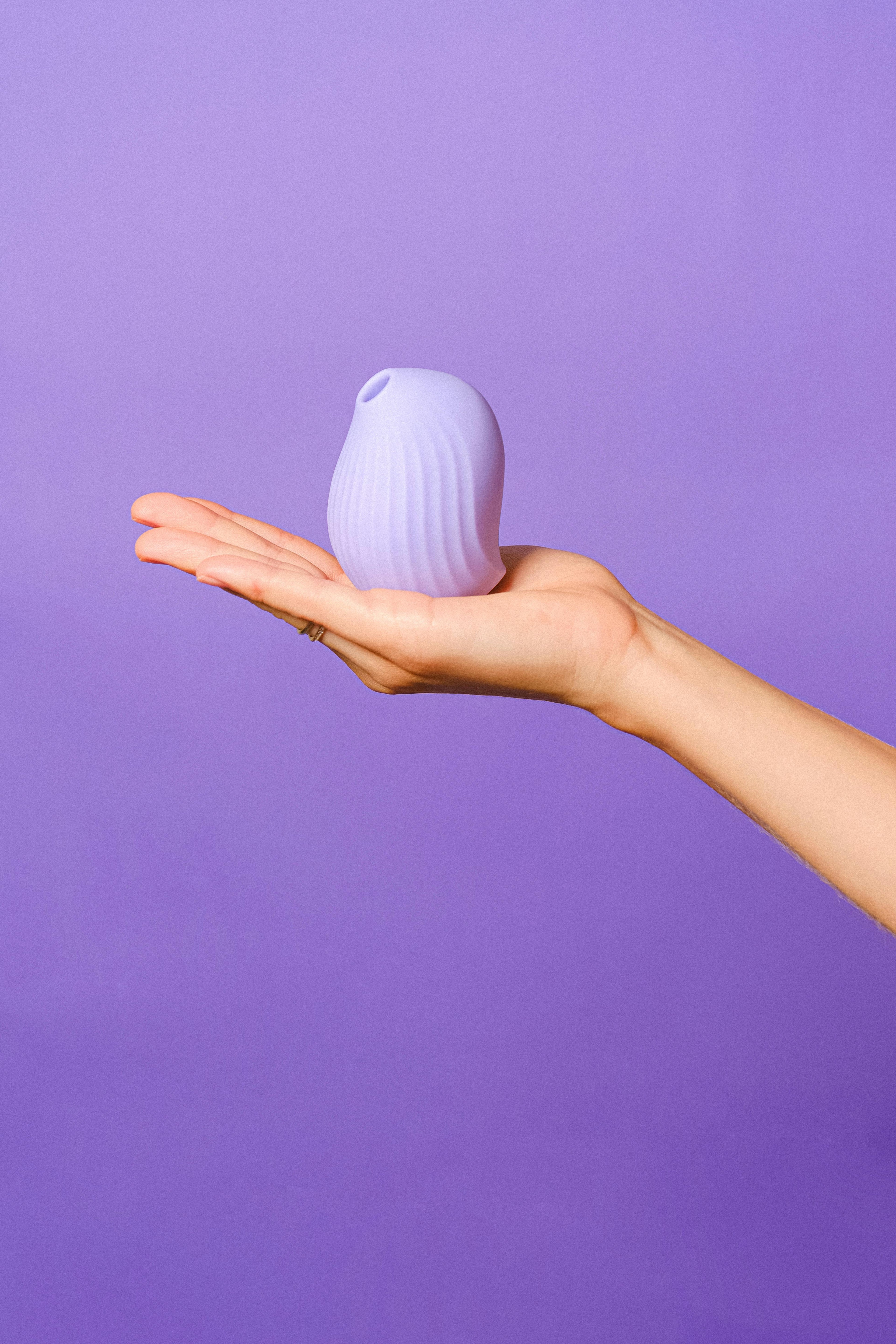 Hand holding a purple pulse vibrator , clitoral stimulator product