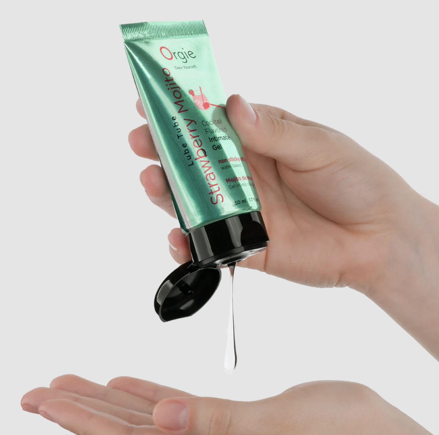 Hand holding a green tube of personal lubricant with a white background