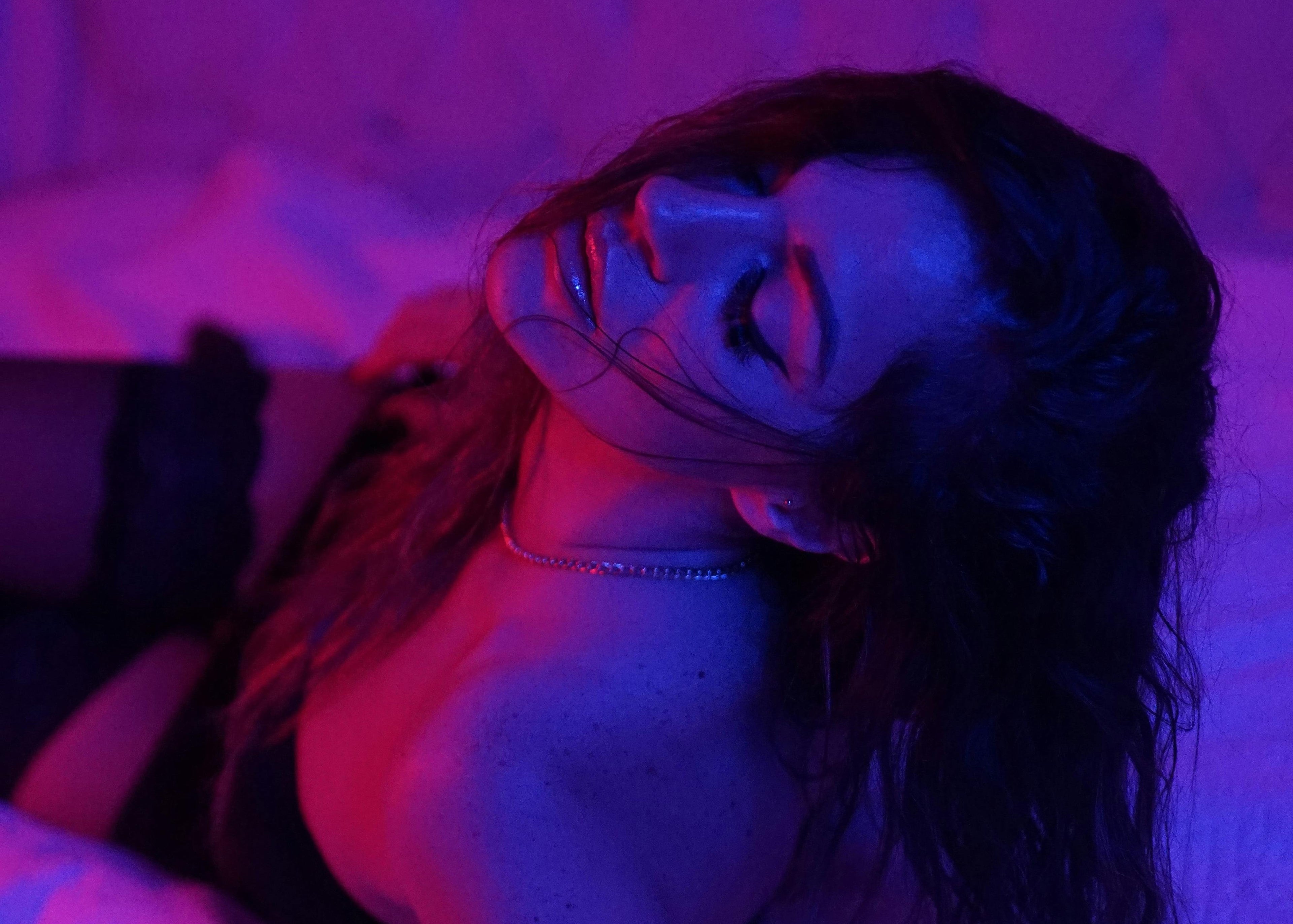 Woman in sexy lingerie lying down with a purple and blue light effect