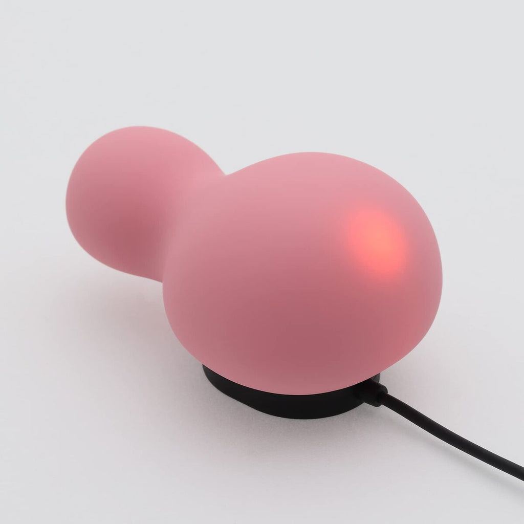 rechargeable pink silicone pleasure toy for women on a charging dock over a white background