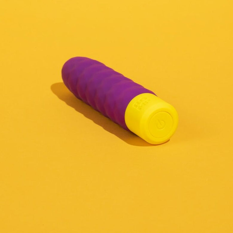 Purple and yellow adult pleasure toy on a mustard yellow background