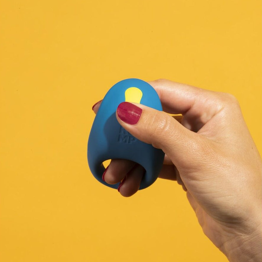 Hand holding a blue and yellow sexual wellness device against a yellow background