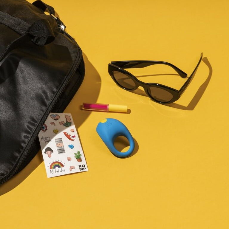 Black bag, sunglasses, penis ring and other colorful items on a yellow background