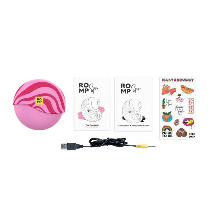 Pink electronic sexual wellness device with USB cable and stickers on a white background