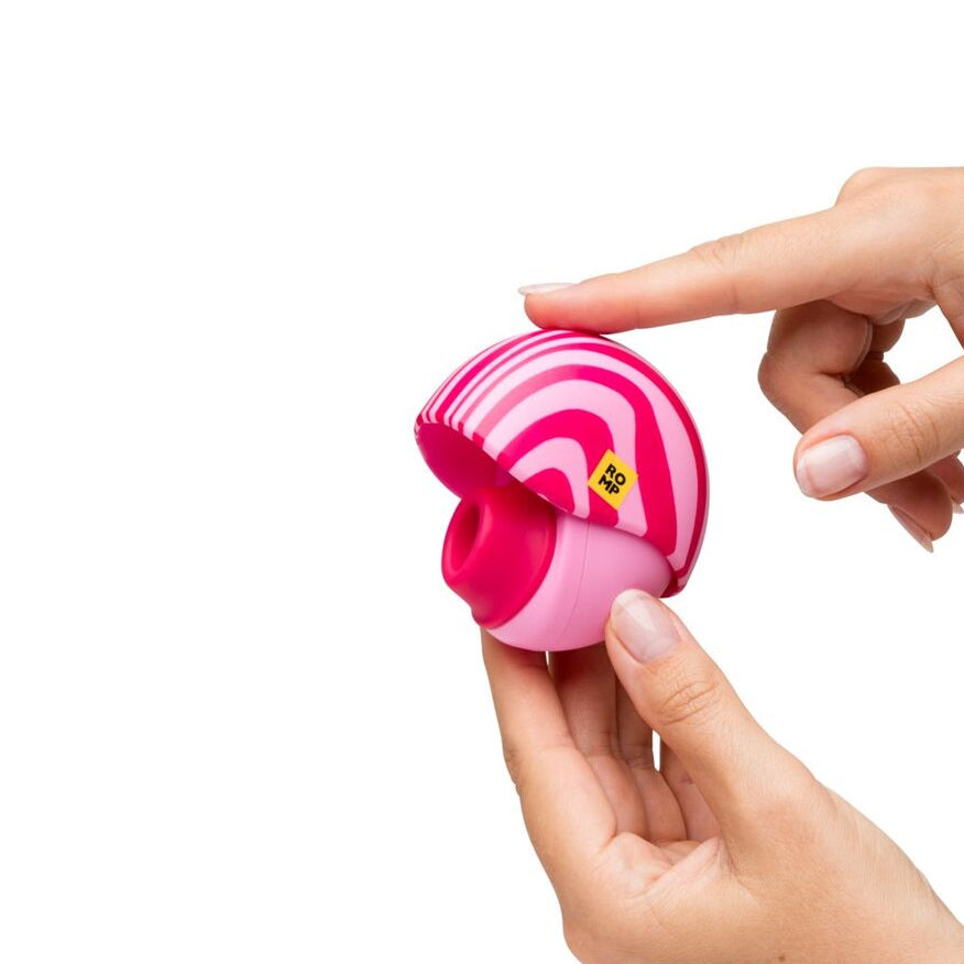 Pink and white pleasure device with a button being pressed by a hand on a white background