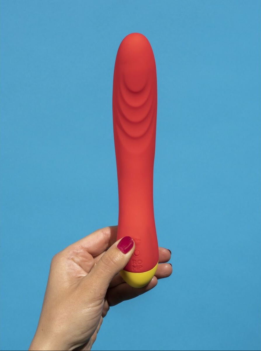 Red and yellow dildo held by a hand against a blue background