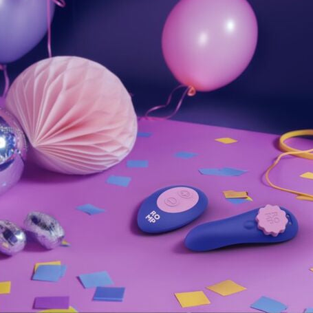 Colorful party supplies including balloons and decorations and panty vibrator on a purple surface.
