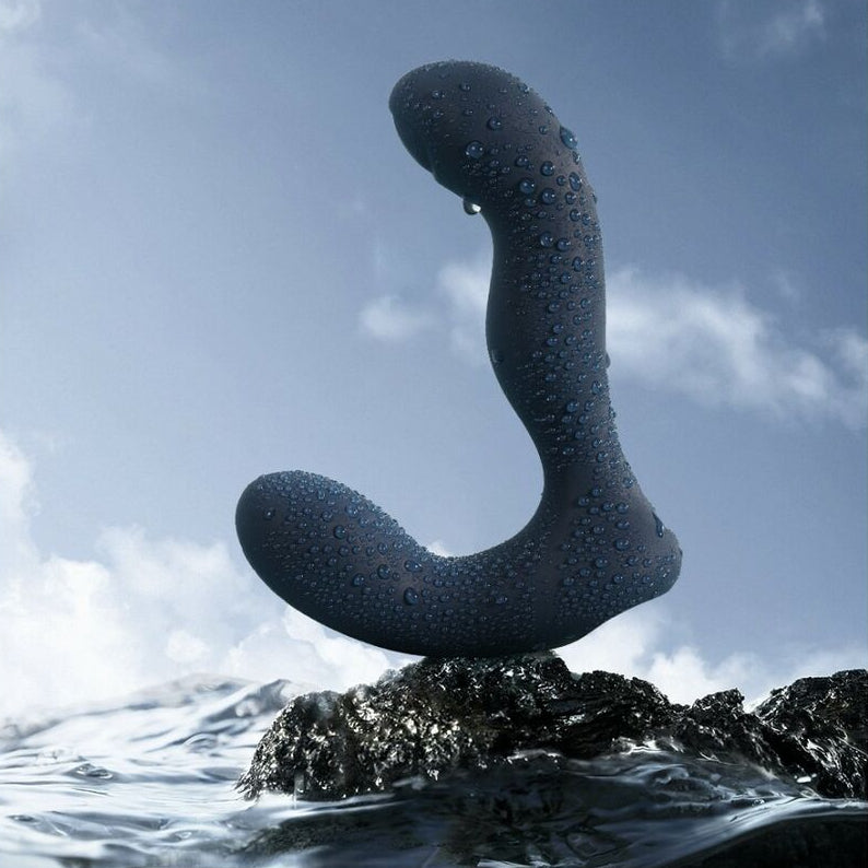 Rock formation with water droplets and a navy blue sexual wellness device for men against a blue sky