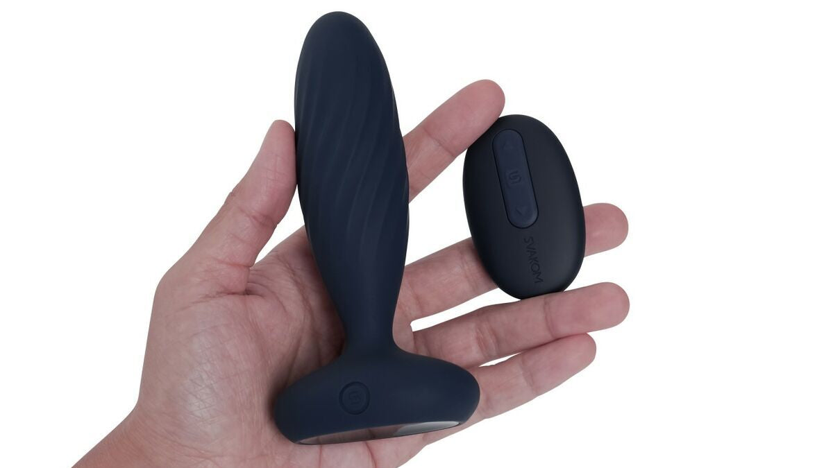 Black silicone butt plug with remote control on a hand against a white background