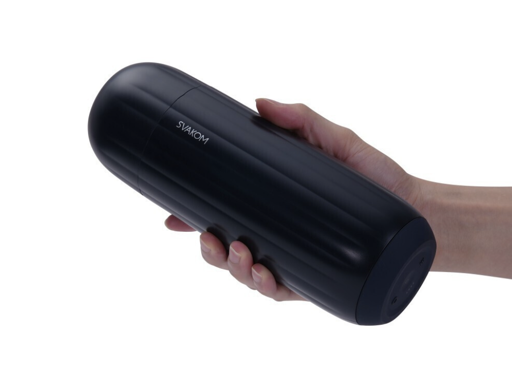 Black cylindrical erotic product held by a hand on a white background
