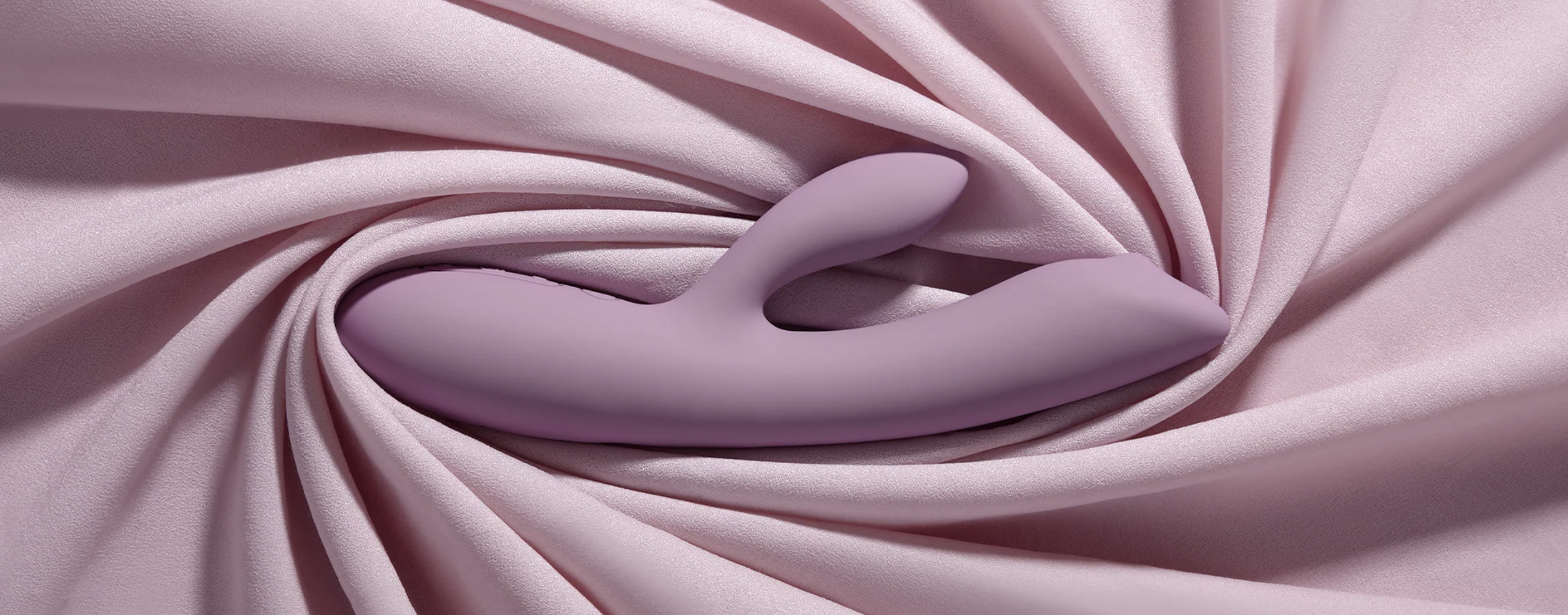 Close-up of purple wand massager with pink fabric with folds