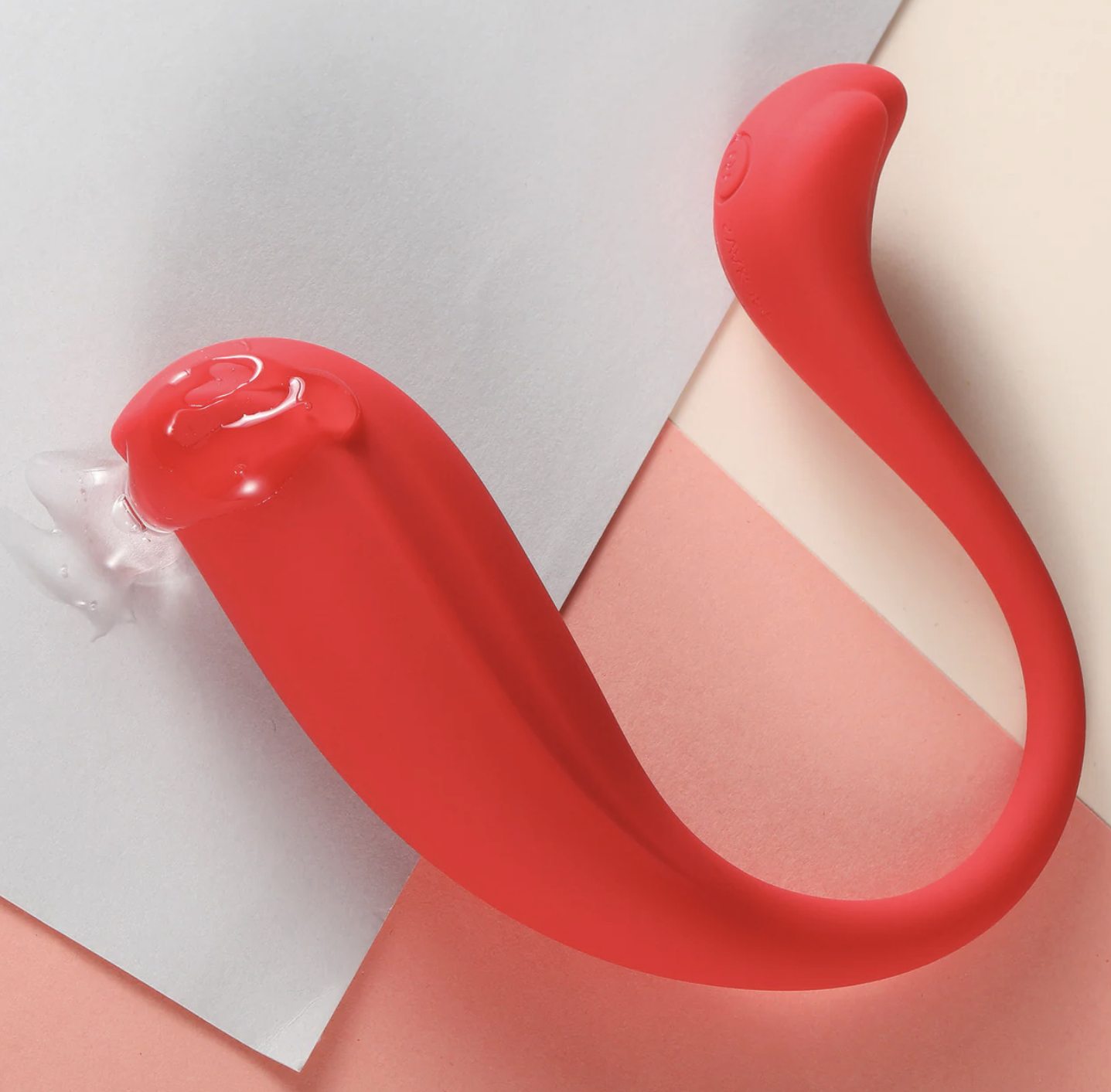 Red silicone erotic product on a pink and gray gradient background