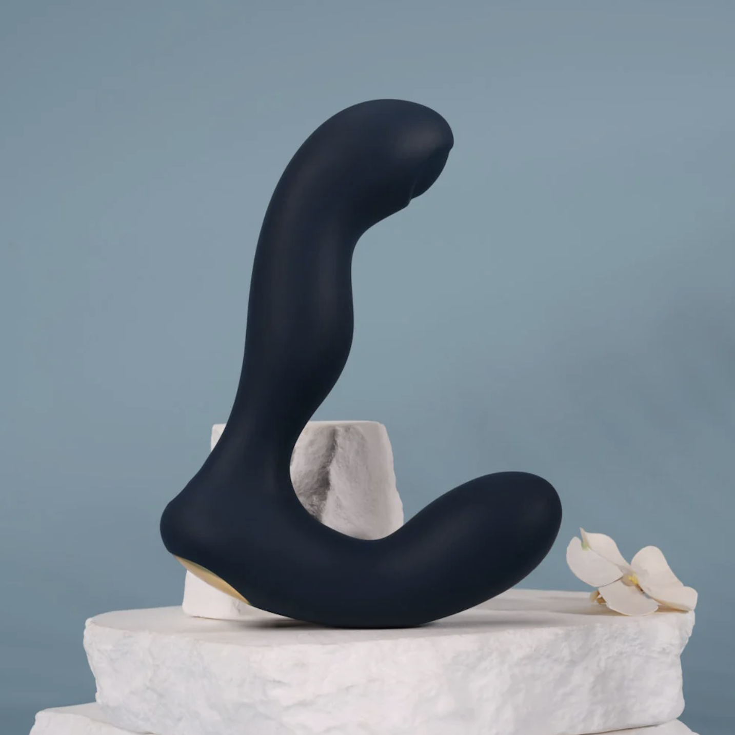 Black butt plug sculpture on a white pedestal against a gray background