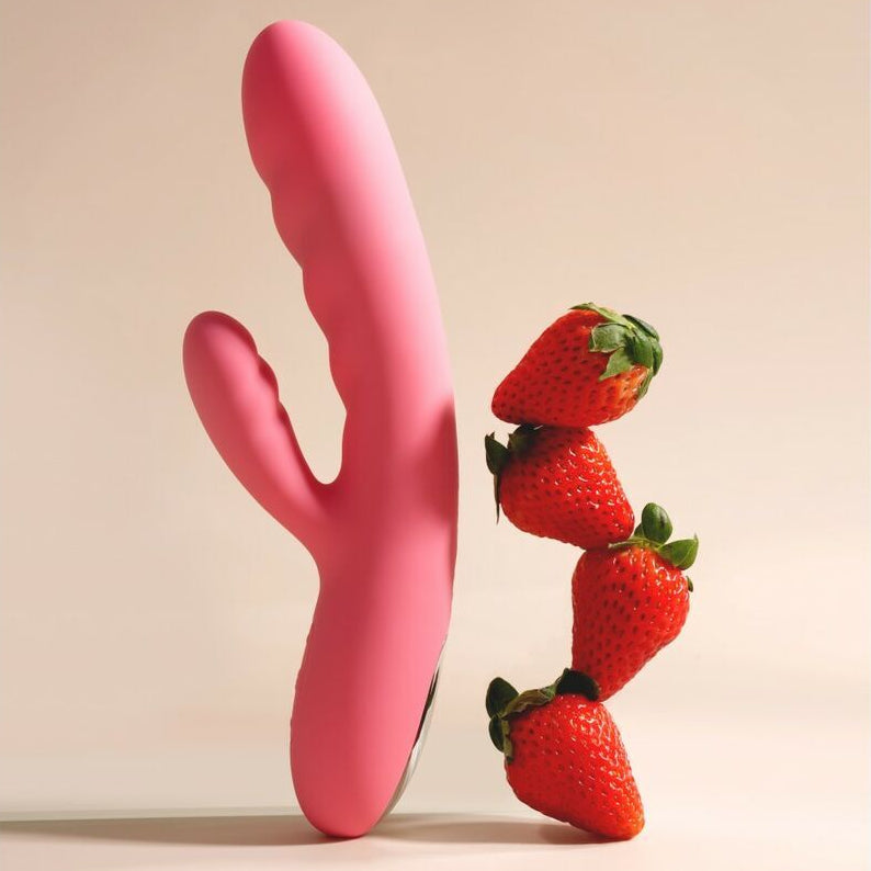 Pink curved adult pleasure toy with strawberries on a beige background