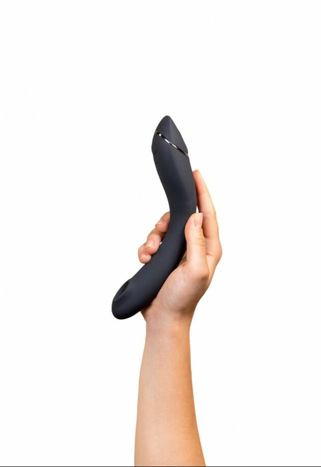 Hand holding a black vibrator against a white background