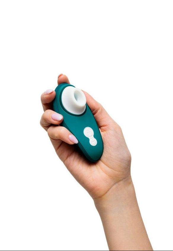 Hand holding a teal and white pleasure toy on a white background