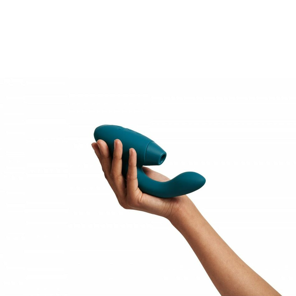 Hand holding a teal-colored sexual wellness product against a white background