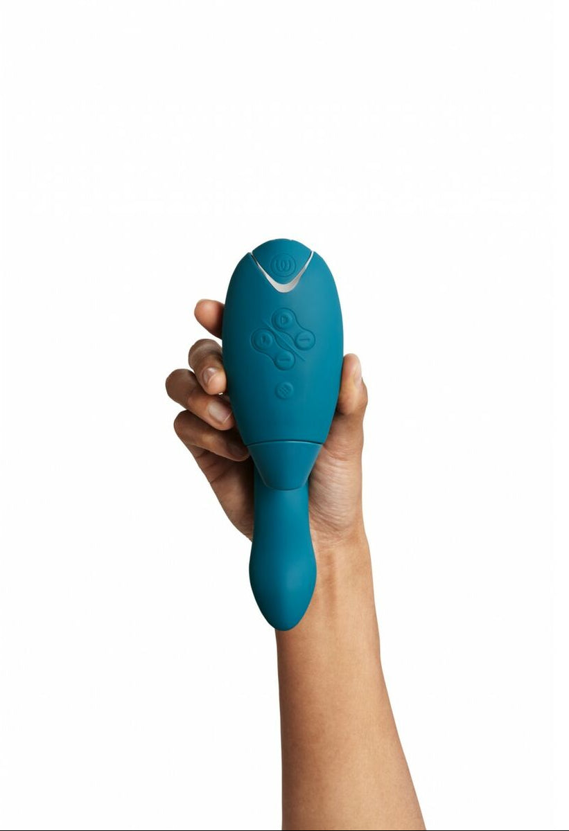Hand holding a teal adult pleasure device with a womanizer brand logo on a white background