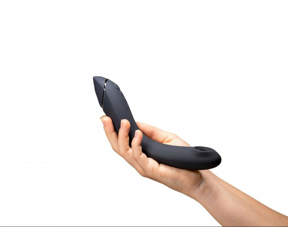 Hand holding a black ergonomic pleasure toy on a white background